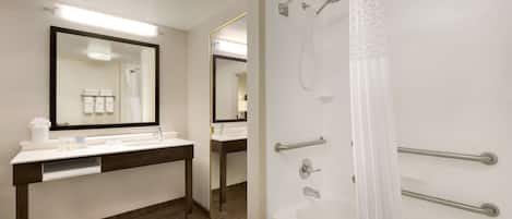 Un baño moderno con lavamanos blanco, espejo y zona de ducha.