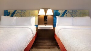 Une chambre d’hôtel avec deux lits, un lavabo central et une lampe fixée au mur.