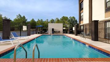 Una piscina al aire libre, sombrillas, sillones reclinables de piscina