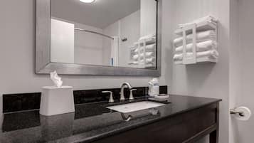 A bathroom with a large mirror, a sink, and a towel rack.