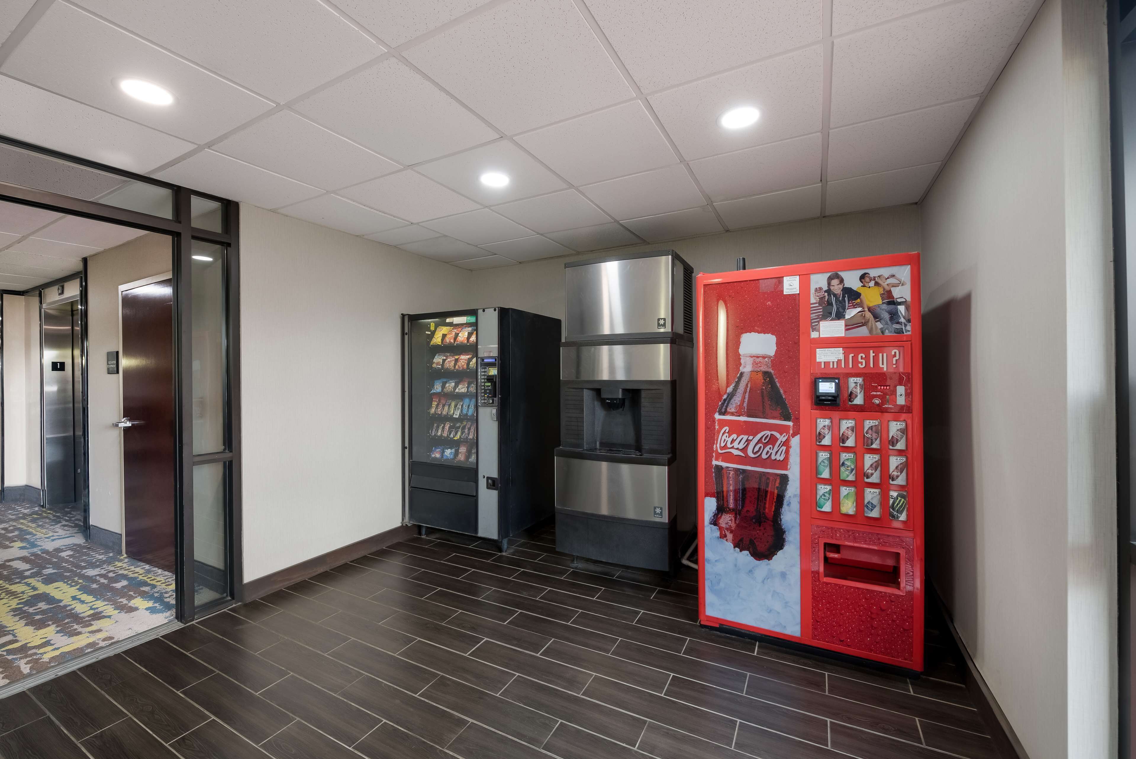 A hallway with vending machines, a water dispenser, and a Coca-Cola branded machine.