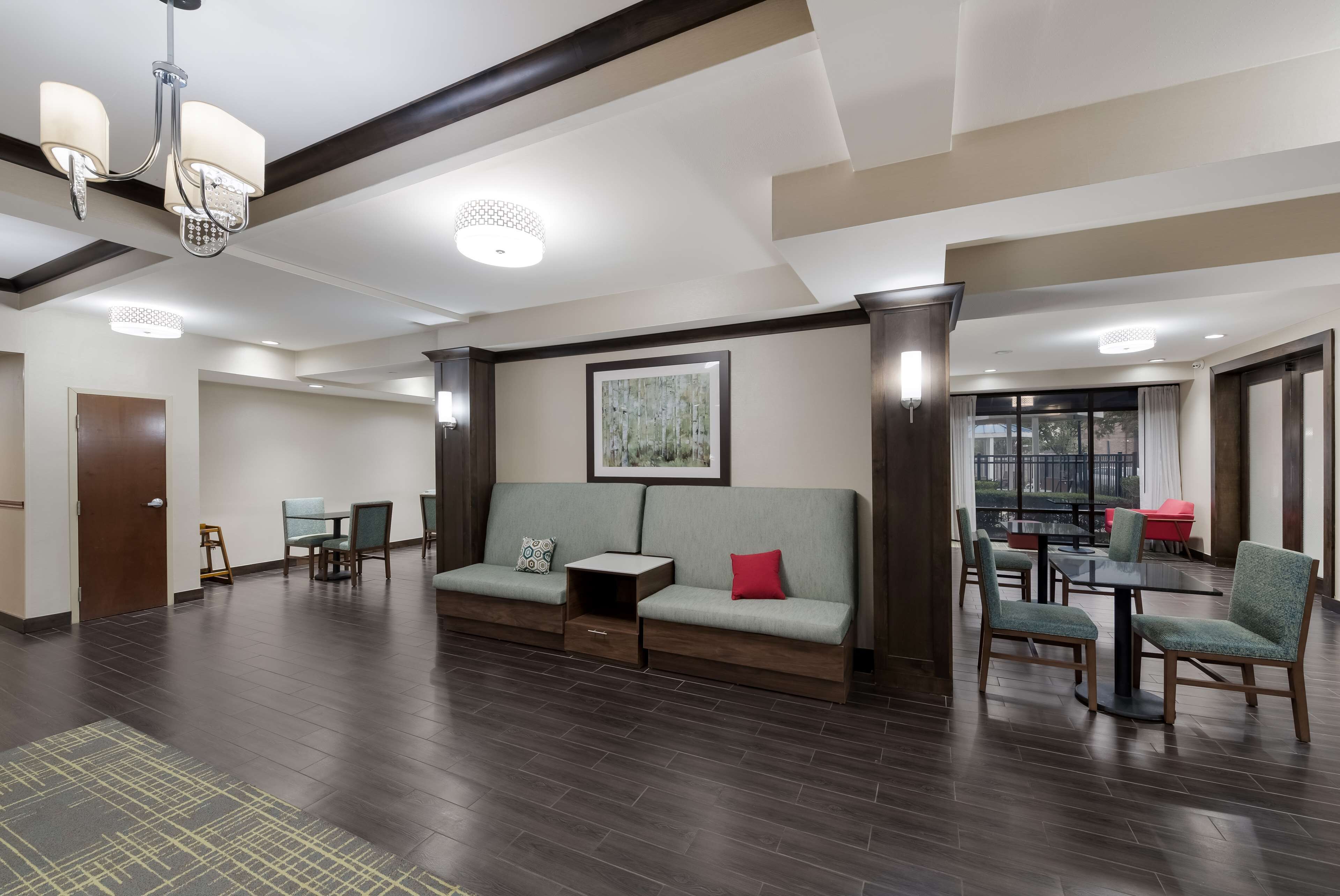 A spacious lobby with a sofa, chairs, a small table, and a chandelier.