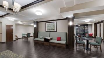 A spacious lobby with a sofa, chairs, a small table, and a chandelier.
