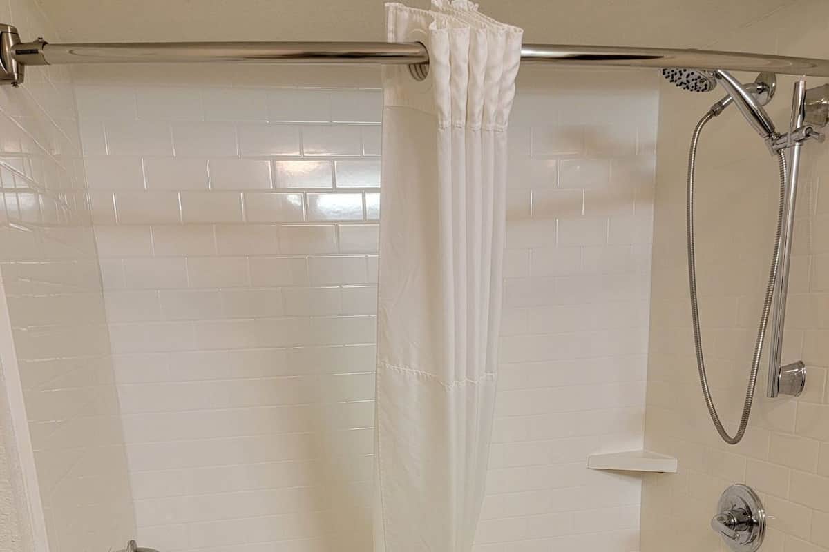 Ducha con puerta de vidrio, cabezal de ducha de mano y toallero.