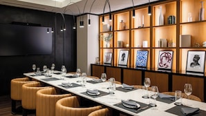 A conference room with a long table, leather chairs, and a wooden shelf with framed pictures and decorative items. - Hyatt Centric Chicago O'Hare (Rosemont)