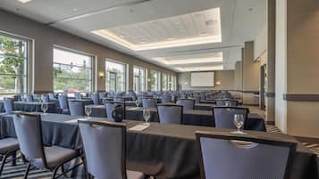 Une salle de conférence équipée de plusieurs tables, de chaises et d’un écran de projection.