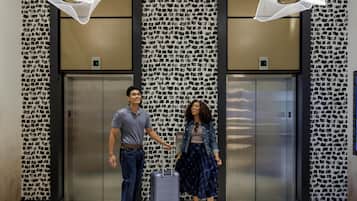 A man and a woman standing in front of elevators with patterned walls and a modern design.