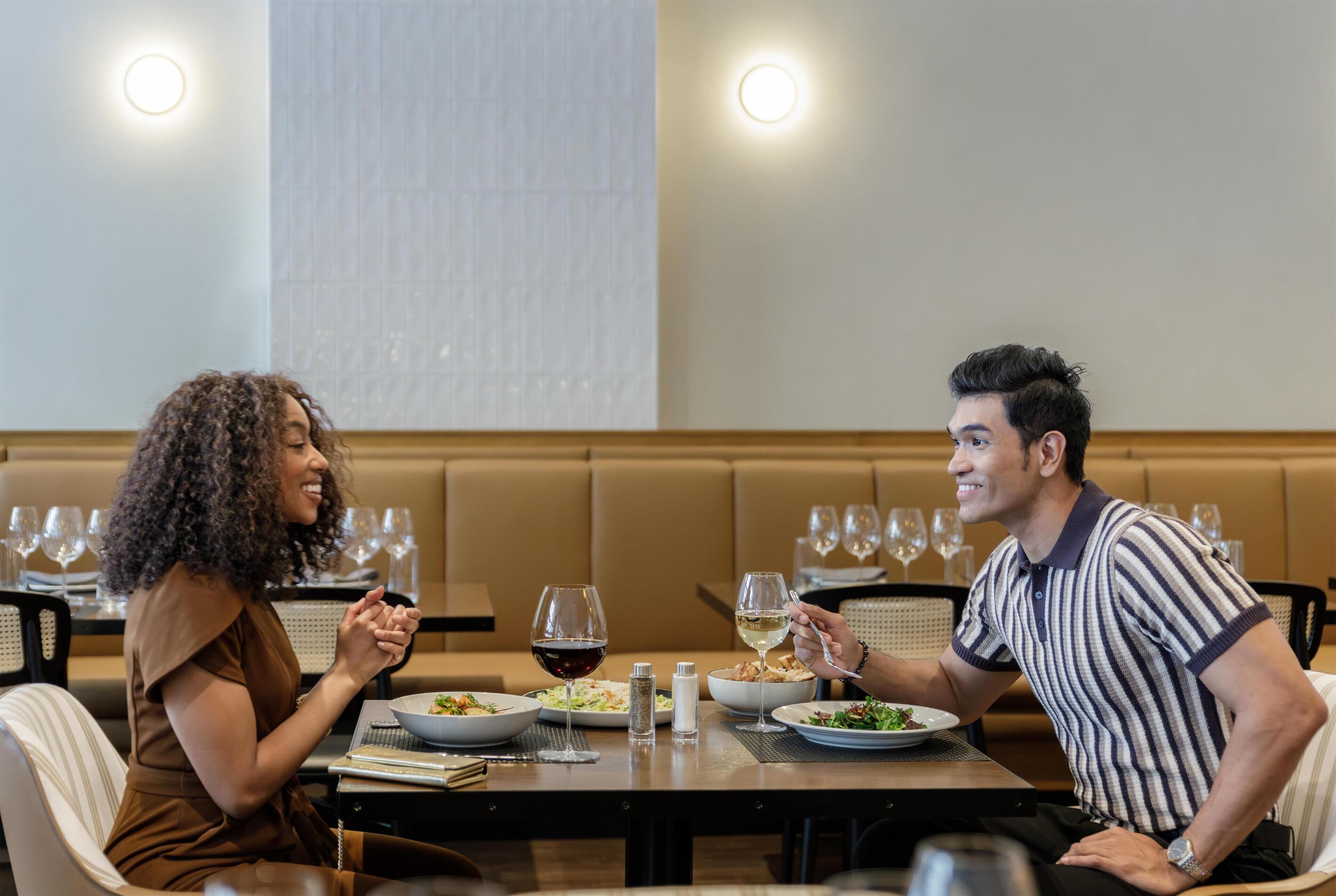 Une table à manger avec des assiettes remplies de nourriture, des verres à vin et un salier.