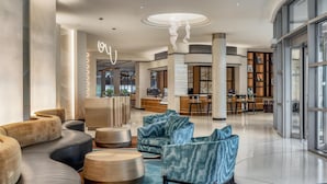 A modern lobby with seating areas, a reception desk, and a bar. - Hyatt Centric Chicago O'Hare (Rosemont)