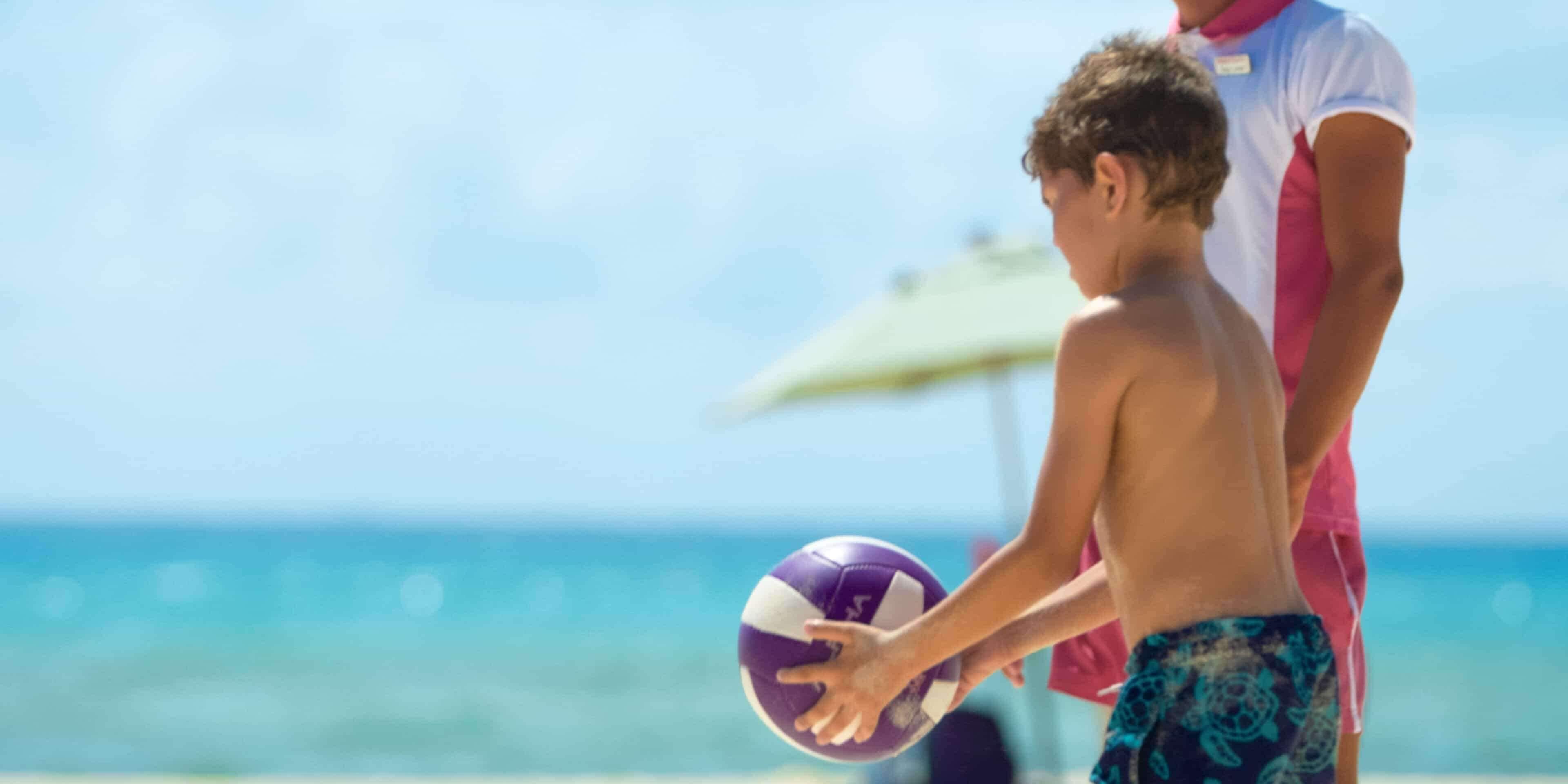 Escena de playa con una pelota de voleibol y una persona en traje de baño.