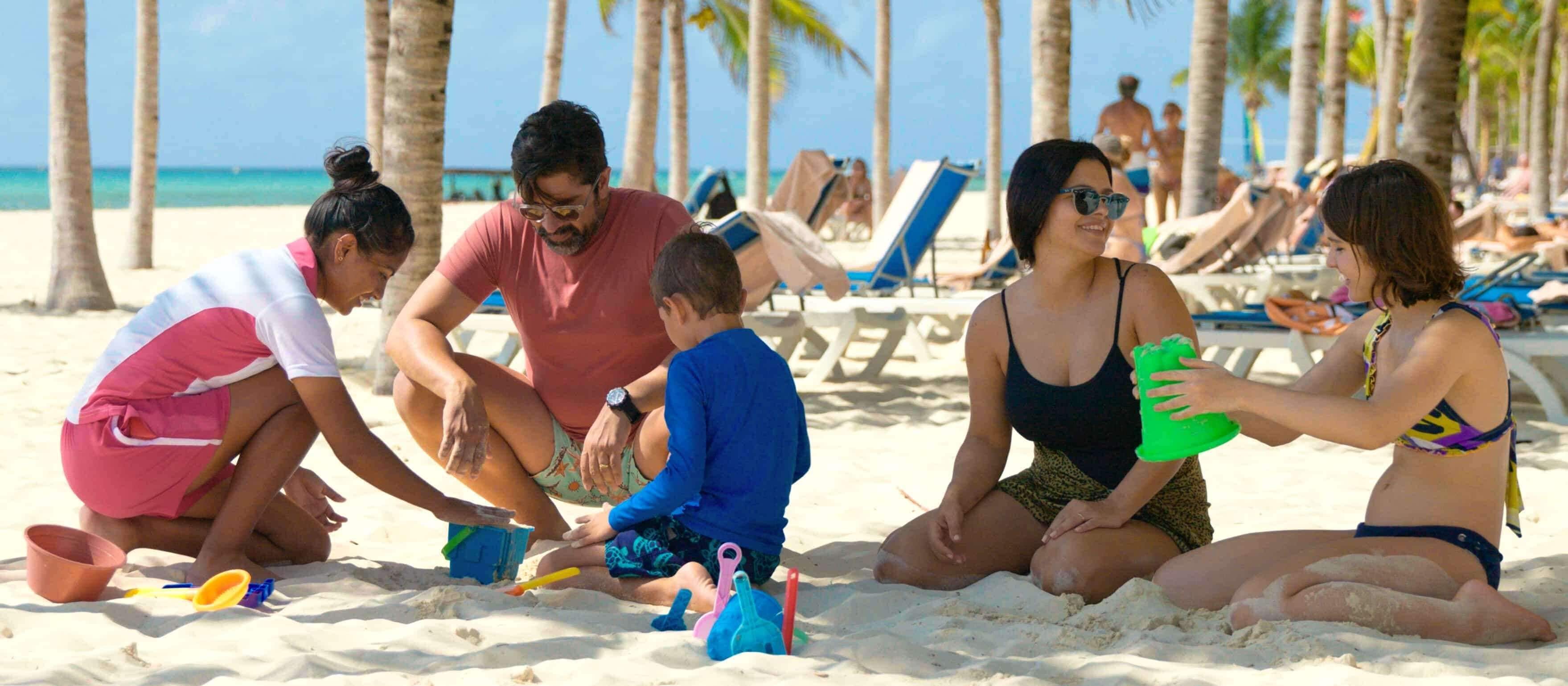 A beach scene with people playing in the sand, palm trees, and beach chairs in the background.