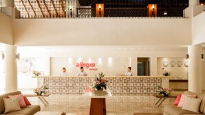 A hotel reception area with a reception desk, two staff members, and a modern interior design.