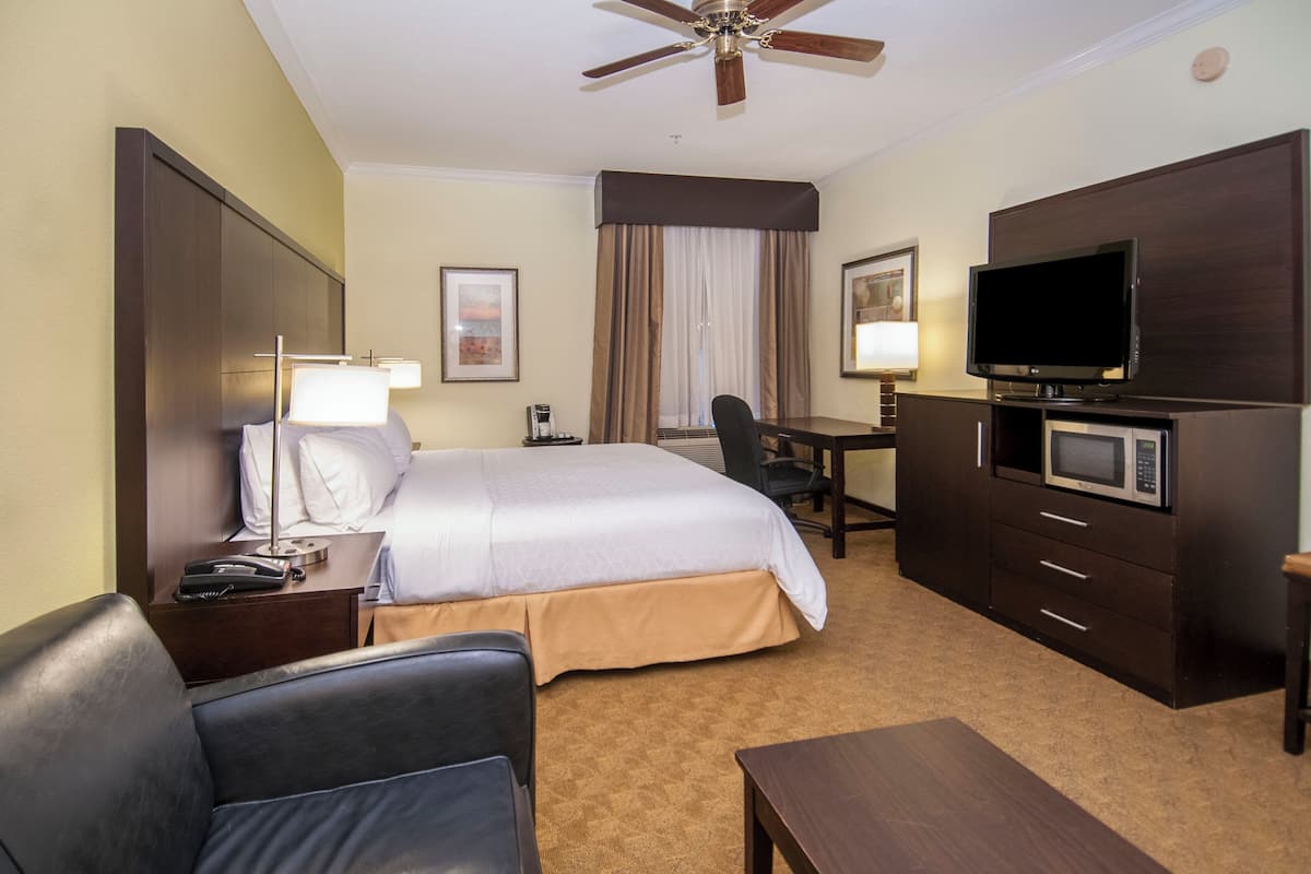 A hotel room with a bed, desk, television, and a ceiling fan.