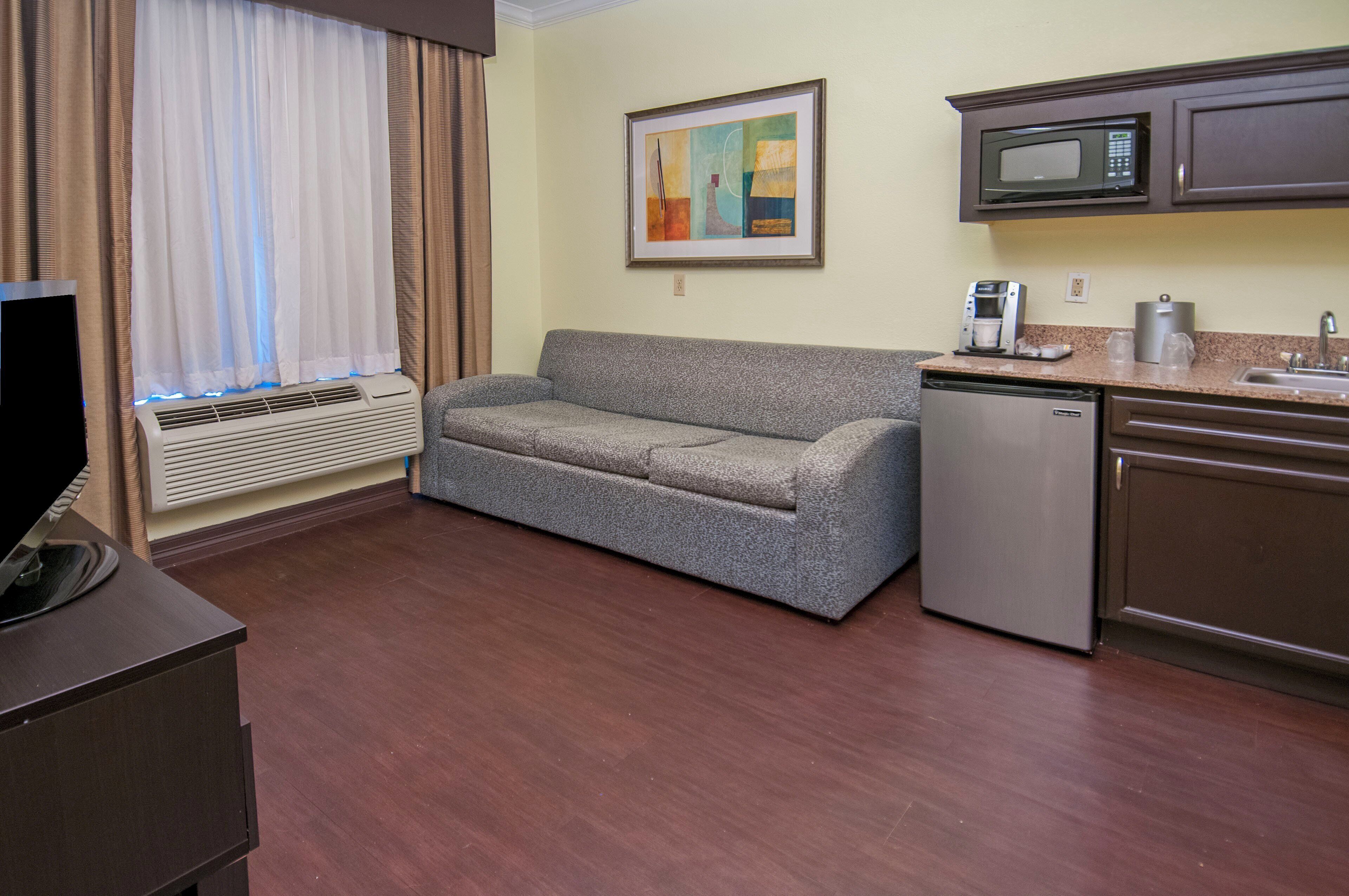 A compact living space with a sofa, a small kitchenette, a microwave, and a coffee maker.