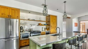 Une cuisine moderne dotée d’appareils électroménagers en acier inoxydable, de meubles en bois et d’un îlot central agrémenté de tabourets de bar.