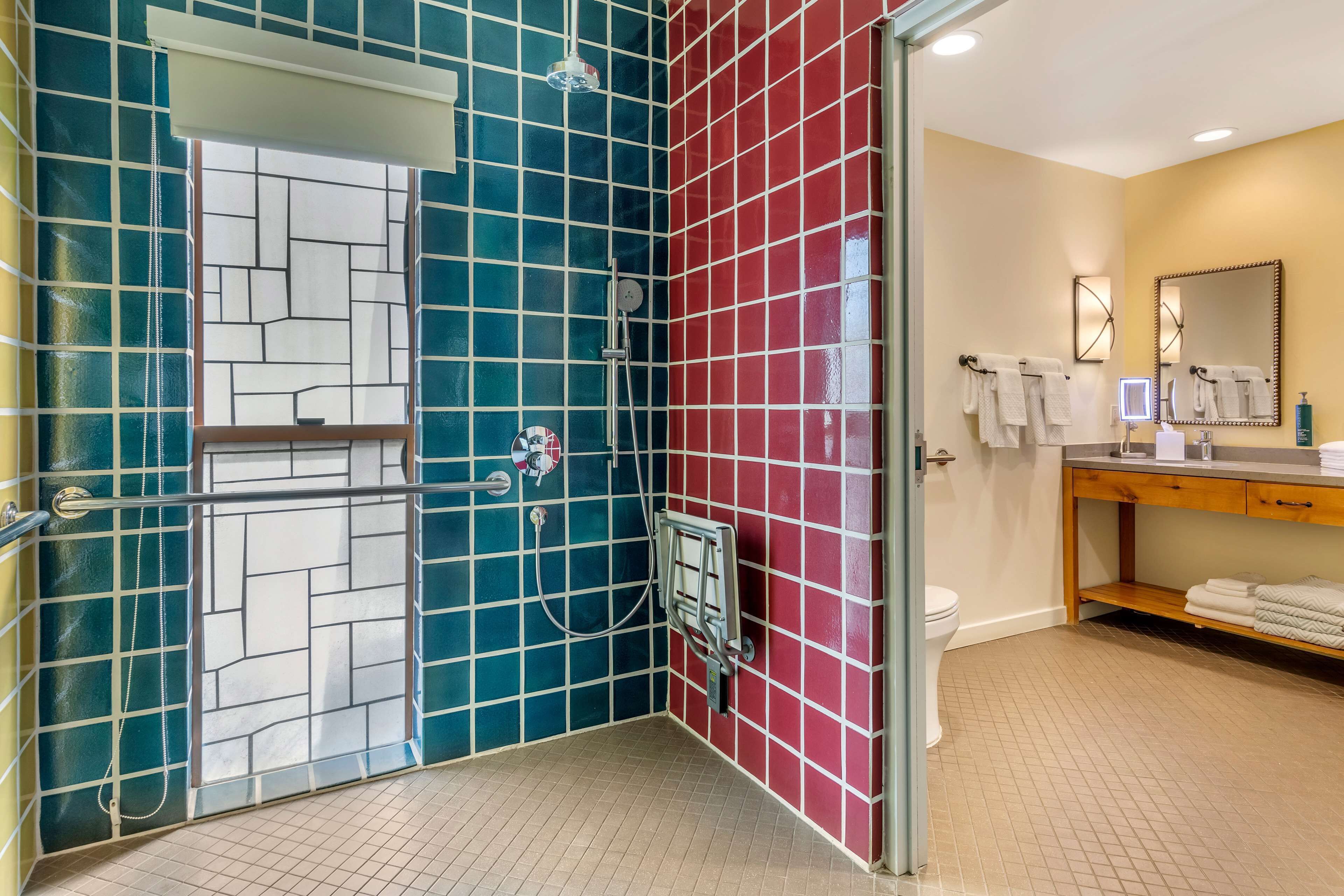 A bathroom with a shower area featuring a glass door, a toilet, and a vanity with a mirror and towel rack.