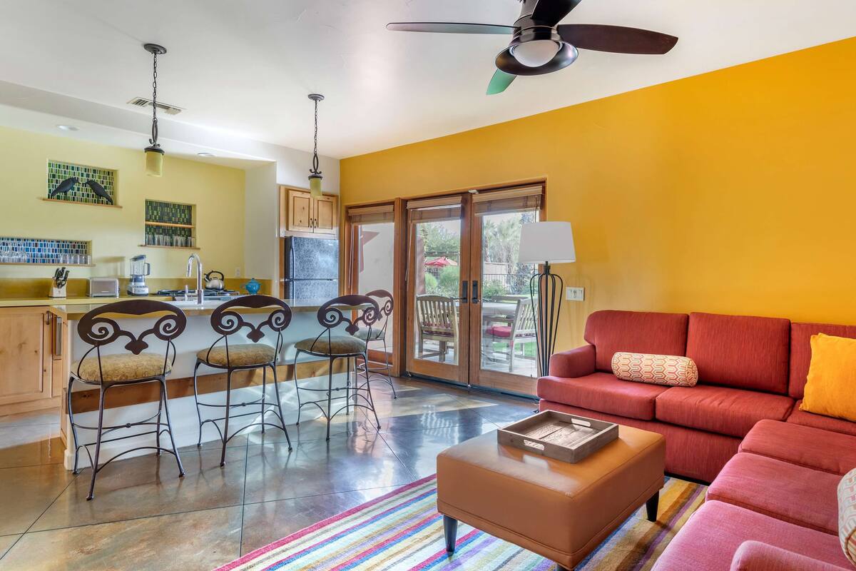 A modern kitchen with a dining area, a red sofa, and a ceiling fan.