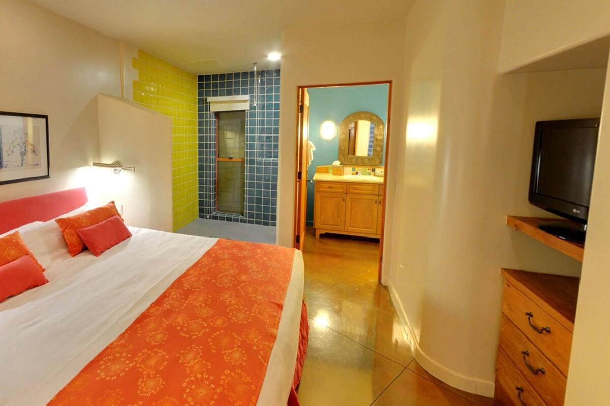 A hotel room with a bed, a television, a bathroom, and a kitchen area.