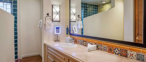A bathroom with a large mirror, a sink, and a vanity with drawers.