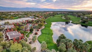 Un parcours de golf avec un lac, entouré de bâtiments et de palmiers.