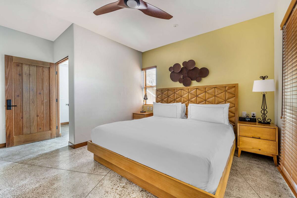 A bedroom with a large bed, wooden headboard, bedside tables, and a ceiling fan.