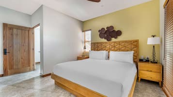 Quarto com uma cama grande, cabeceira de madeira, mesas de cabeceira e um ventilador de teto.