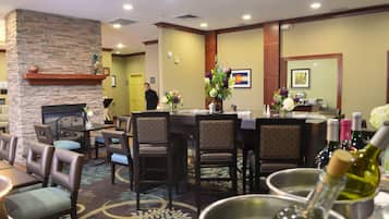 A hotel dining area with a stone fireplace, a bar, and a seating arrangement.