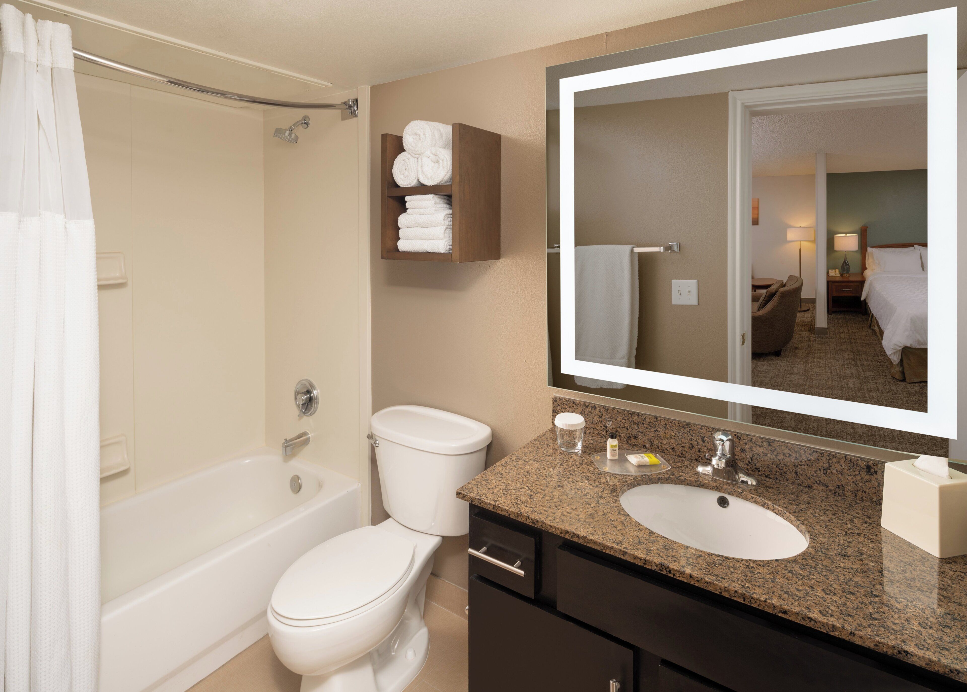 Een hotelbadkamer met een bad, toilet, wastafel en een grote spiegel.