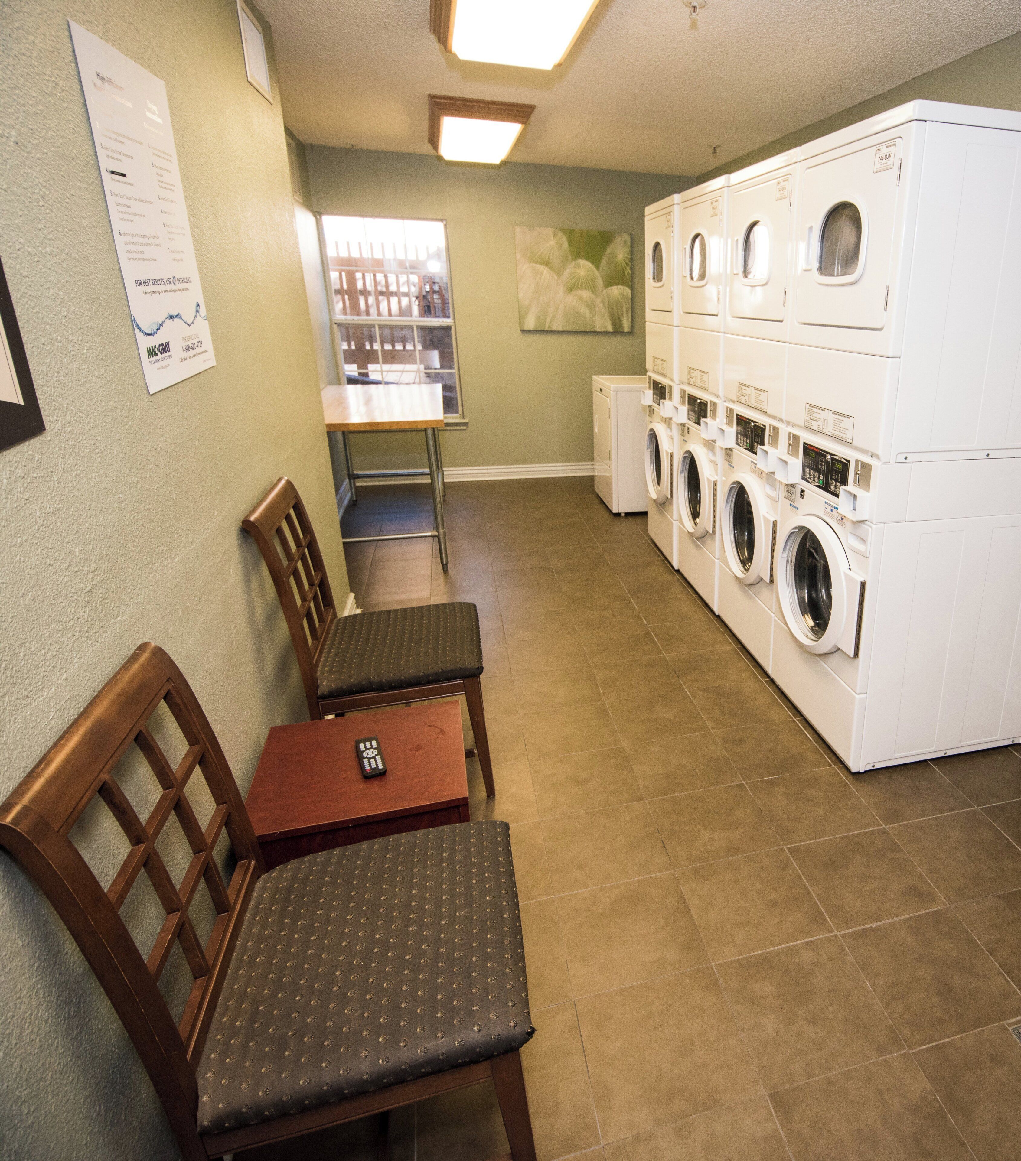 A laundry room with a seating area, a window, and a wall-mounted sign.