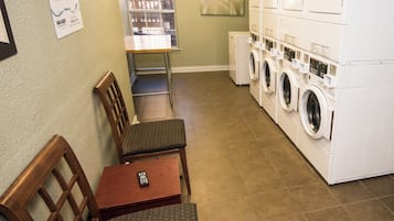 A laundry room with a seating area, a window, and a wall-mounted sign.