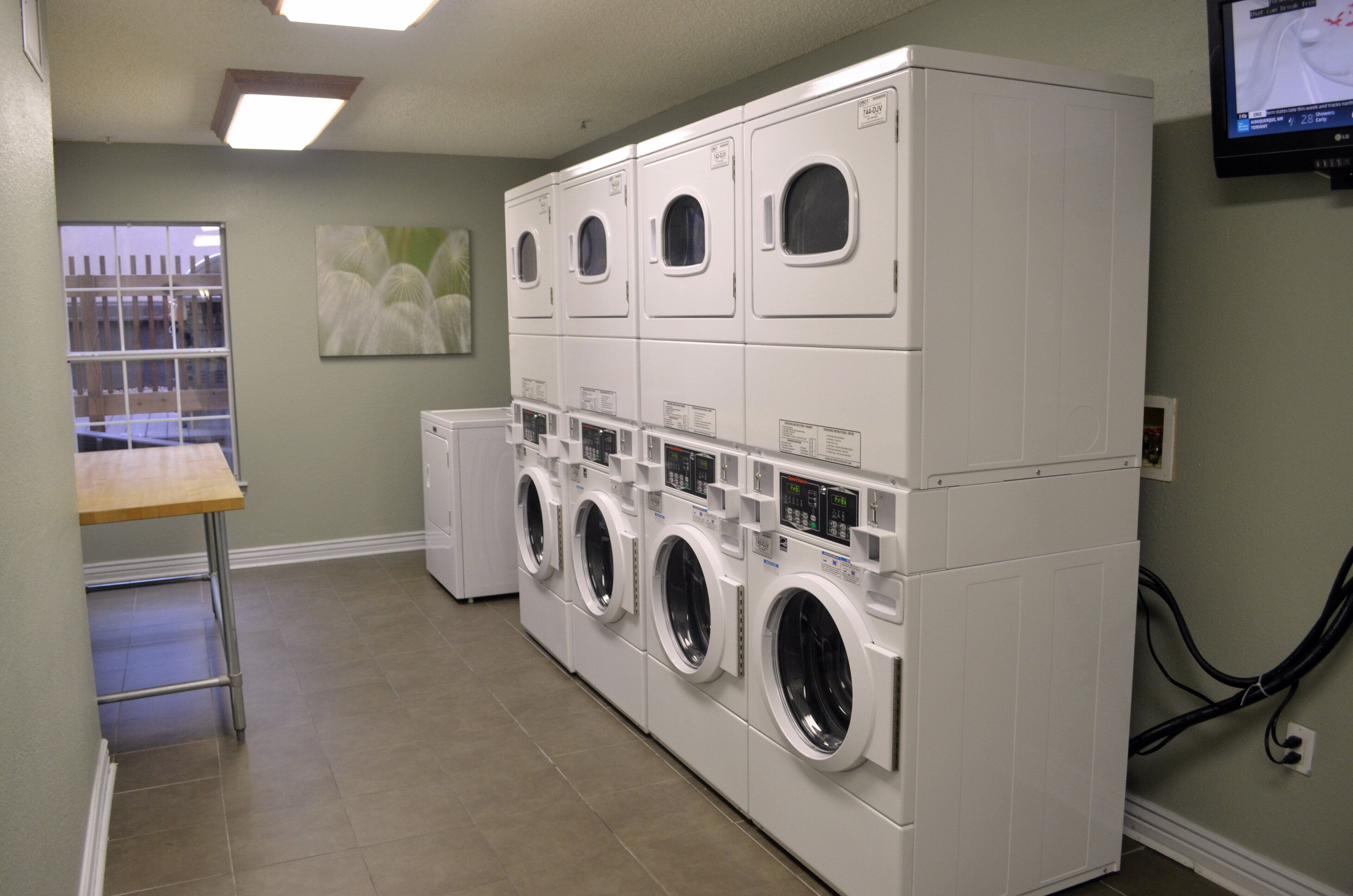 A laundry room with multiple stacked washing machines and a table.
