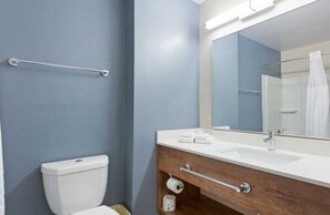 Une salle de bain comprenant des toilettes, un lavabo avec un miroir et un porte-serviettes.
