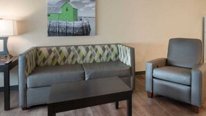 A living room with a sofa, armchair, and coffee table. - Extended Stay America Suites Oakland Alameda Airport (Oakland)