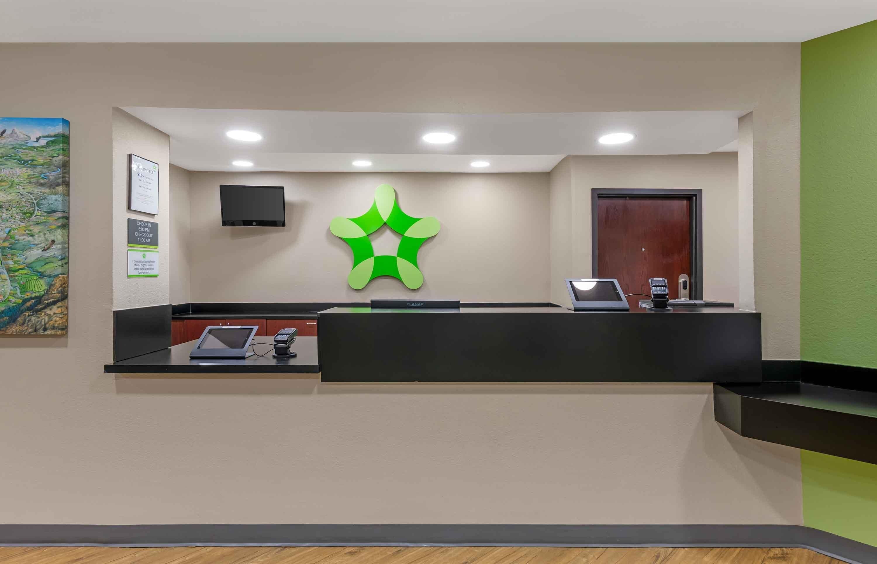 A reception desk with a flat-screen TV, a Planar device, and a telephone.