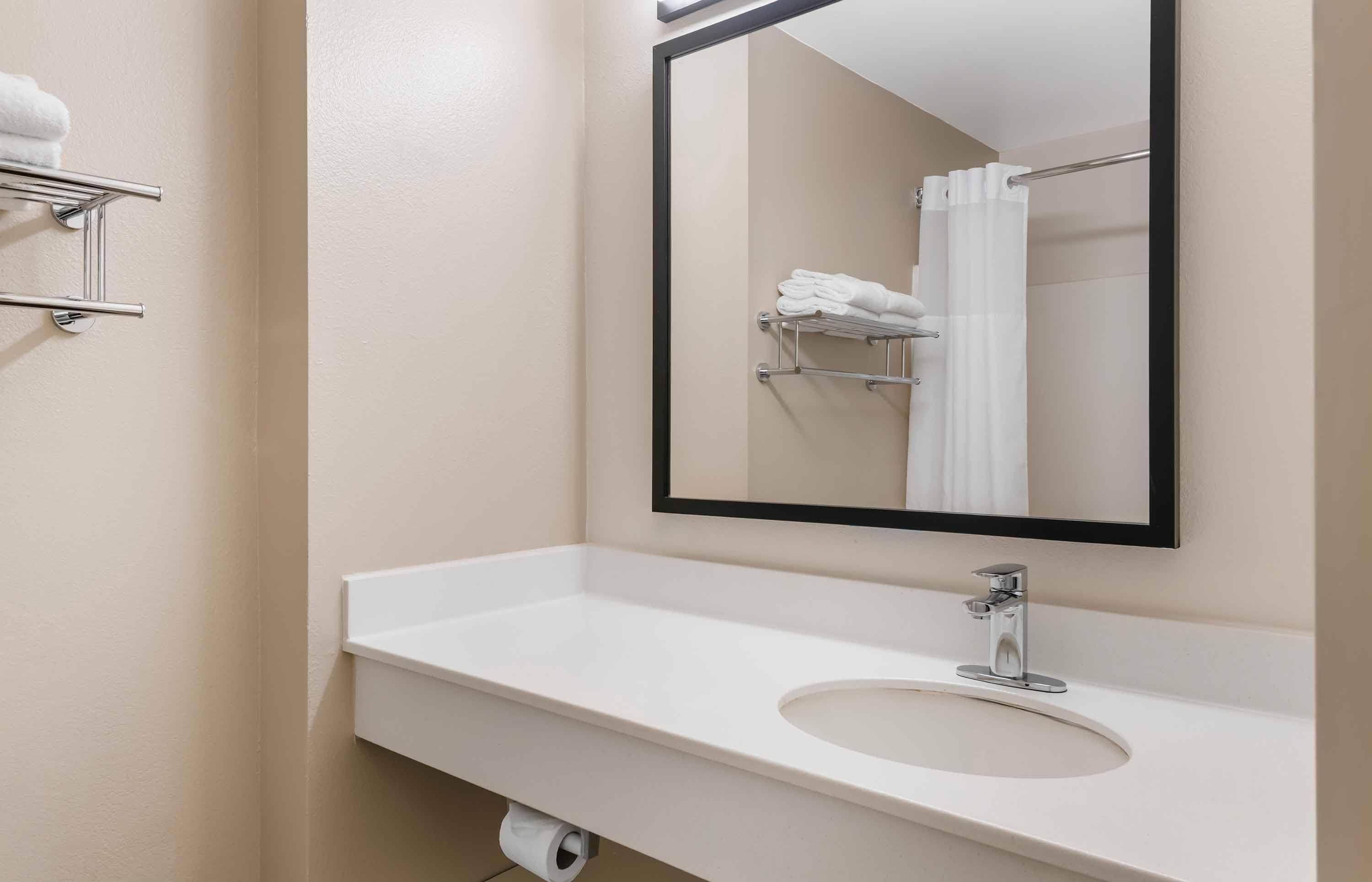A bathroom with a white sink, a mirror, and a towel rack.