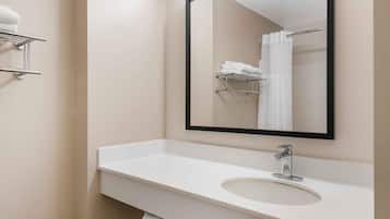 A bathroom with a white sink, a mirror, and a towel rack.