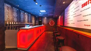 Zona de bar con dardos y una carta que muestra bebidas.