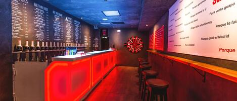 Zona de bar con dardos y una carta que muestra bebidas.