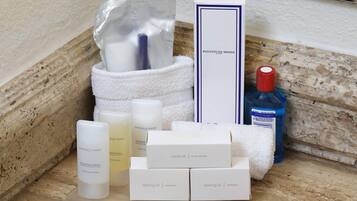 A bathroom vanity with toiletries, including a bottle of blue liquid, a white towel, and a white box labeled "sewing kit."