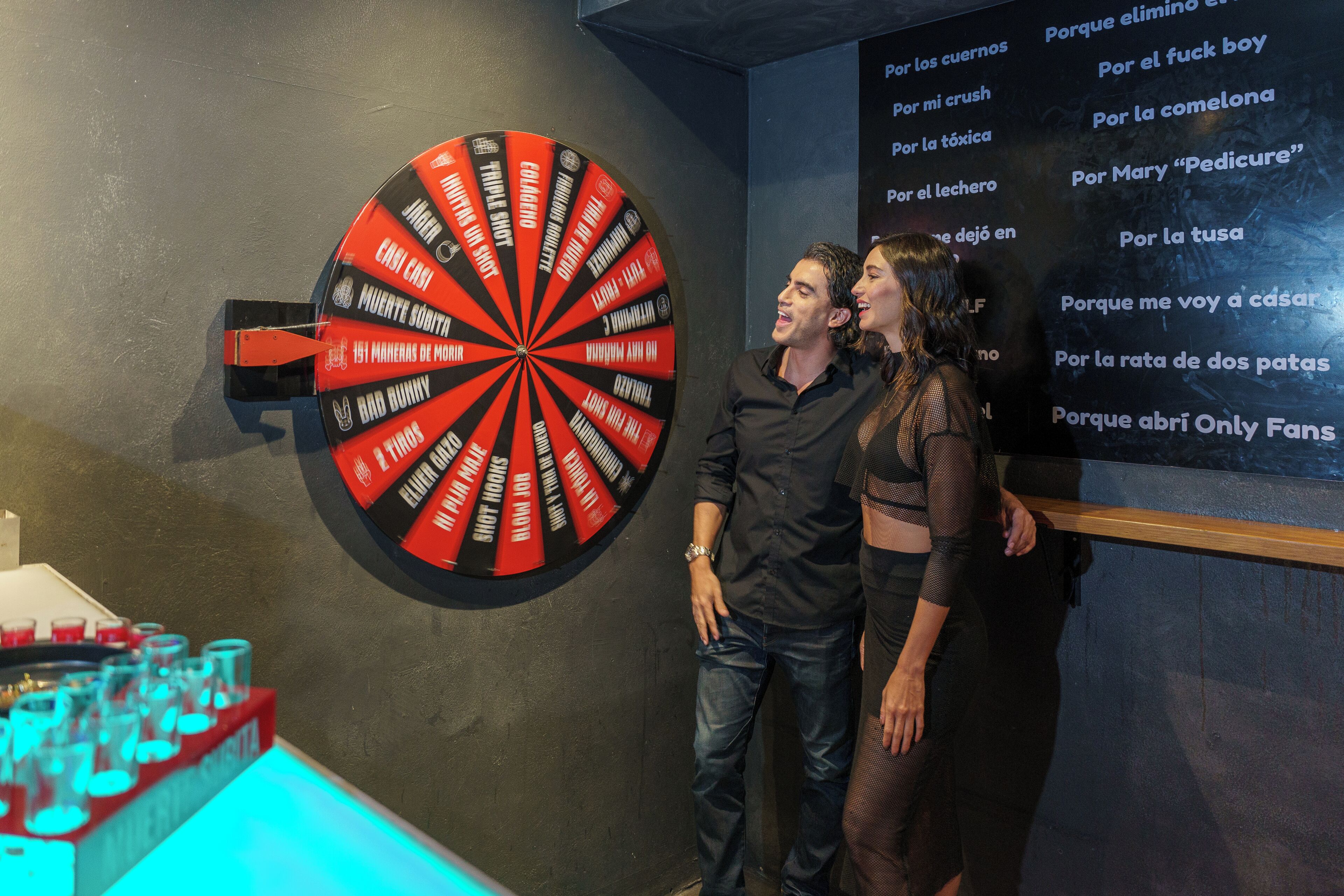 Un dardo con varias frases en español, una pared con texto y una exhibición de objetos rojos y negros.