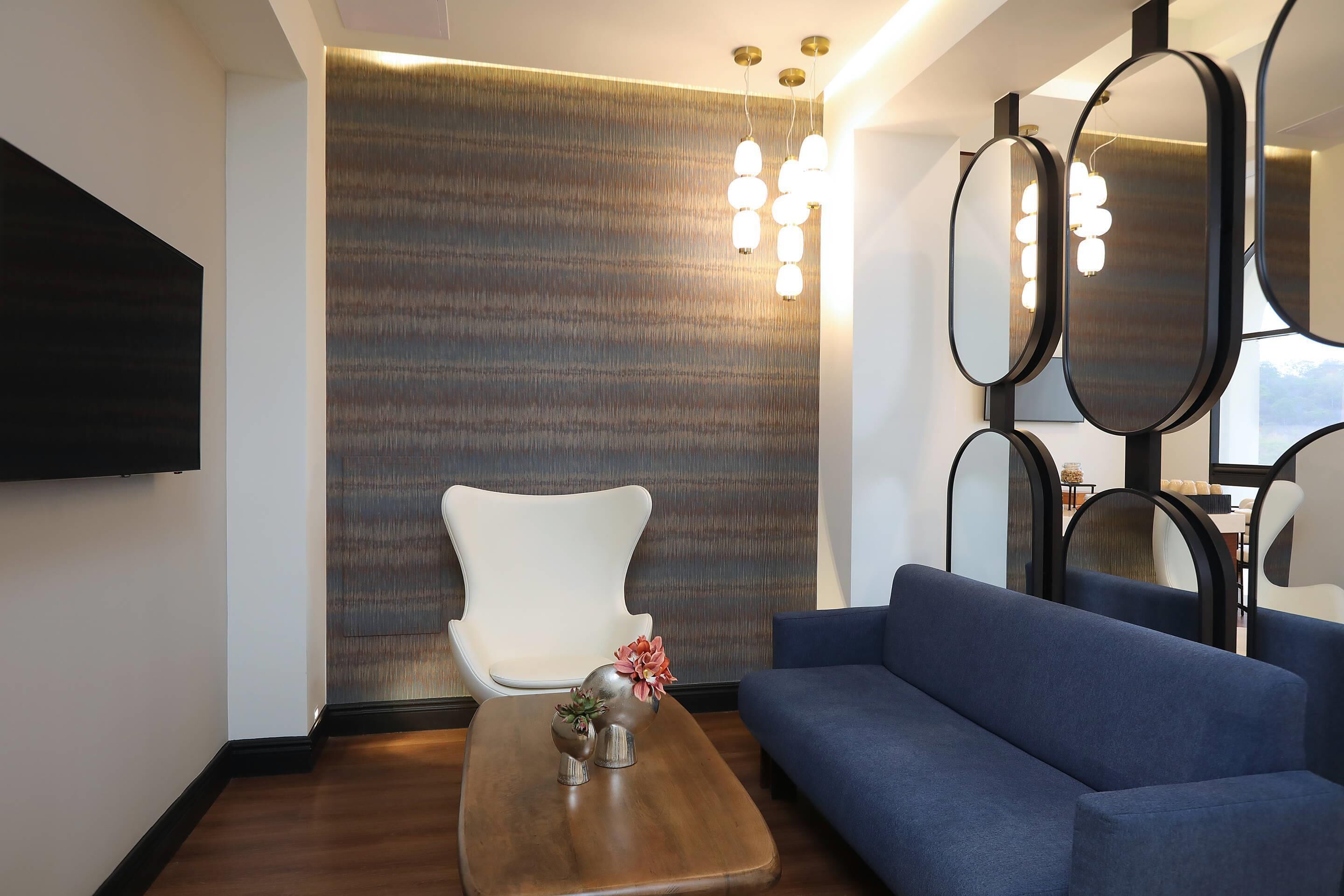 A modern living room with a blue sofa, a white chair, and a wooden coffee table with decorative items.