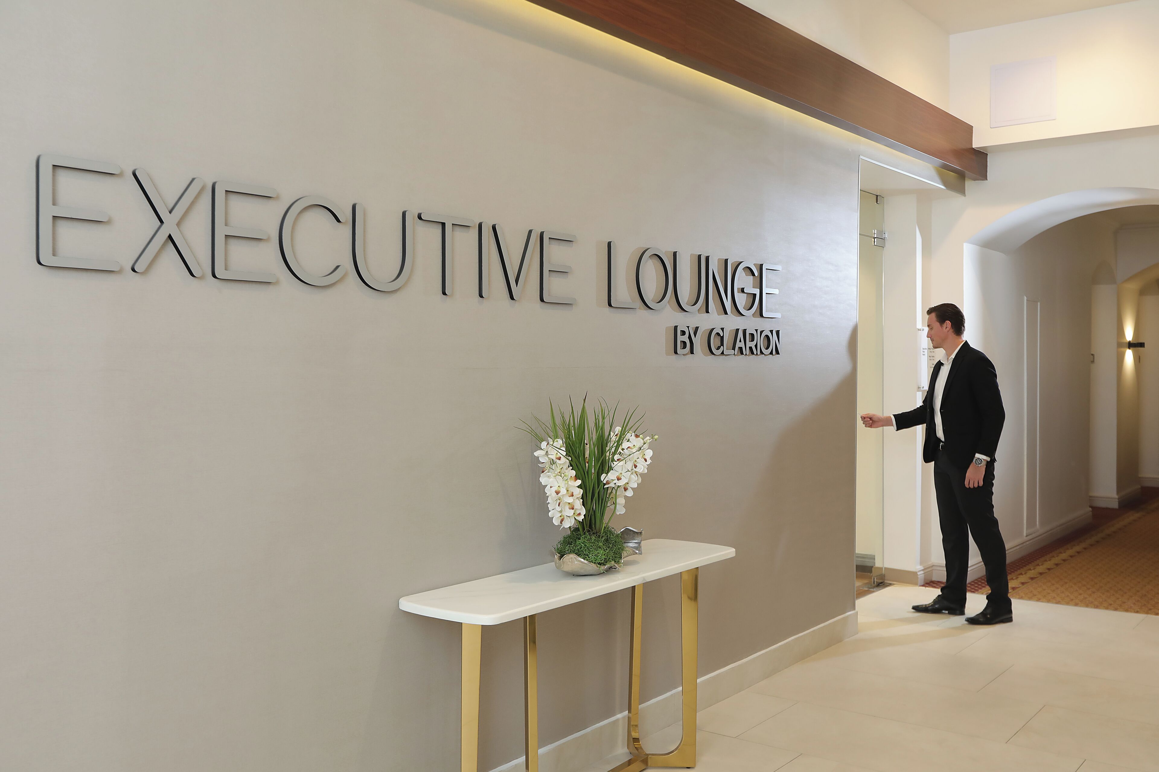 A sign reading "EXECUTIVE LOUNGE BY CLARIO" with a person standing in the doorway.
