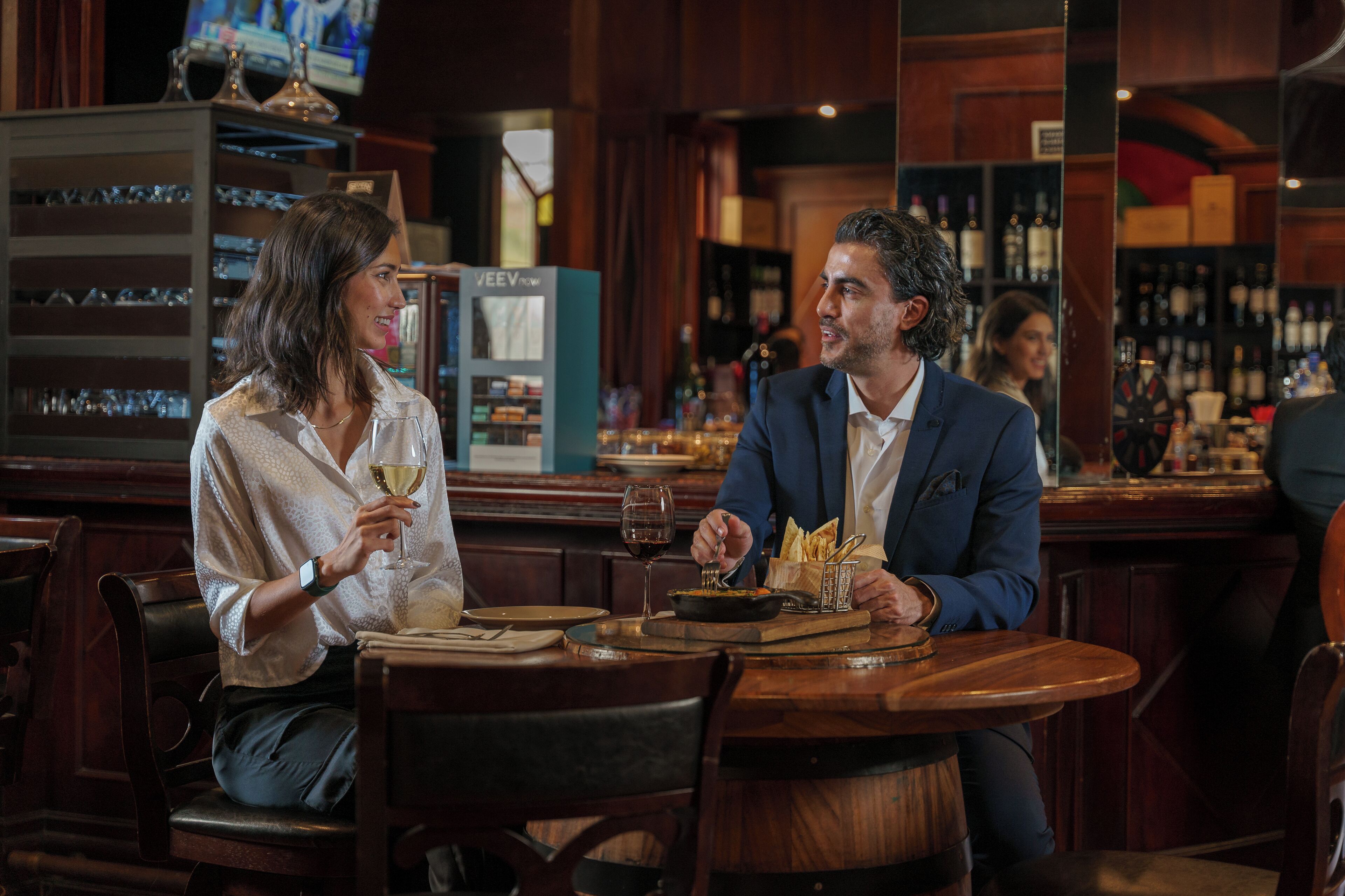A bar setting with wooden furniture, a wine glass, and a menu stand.