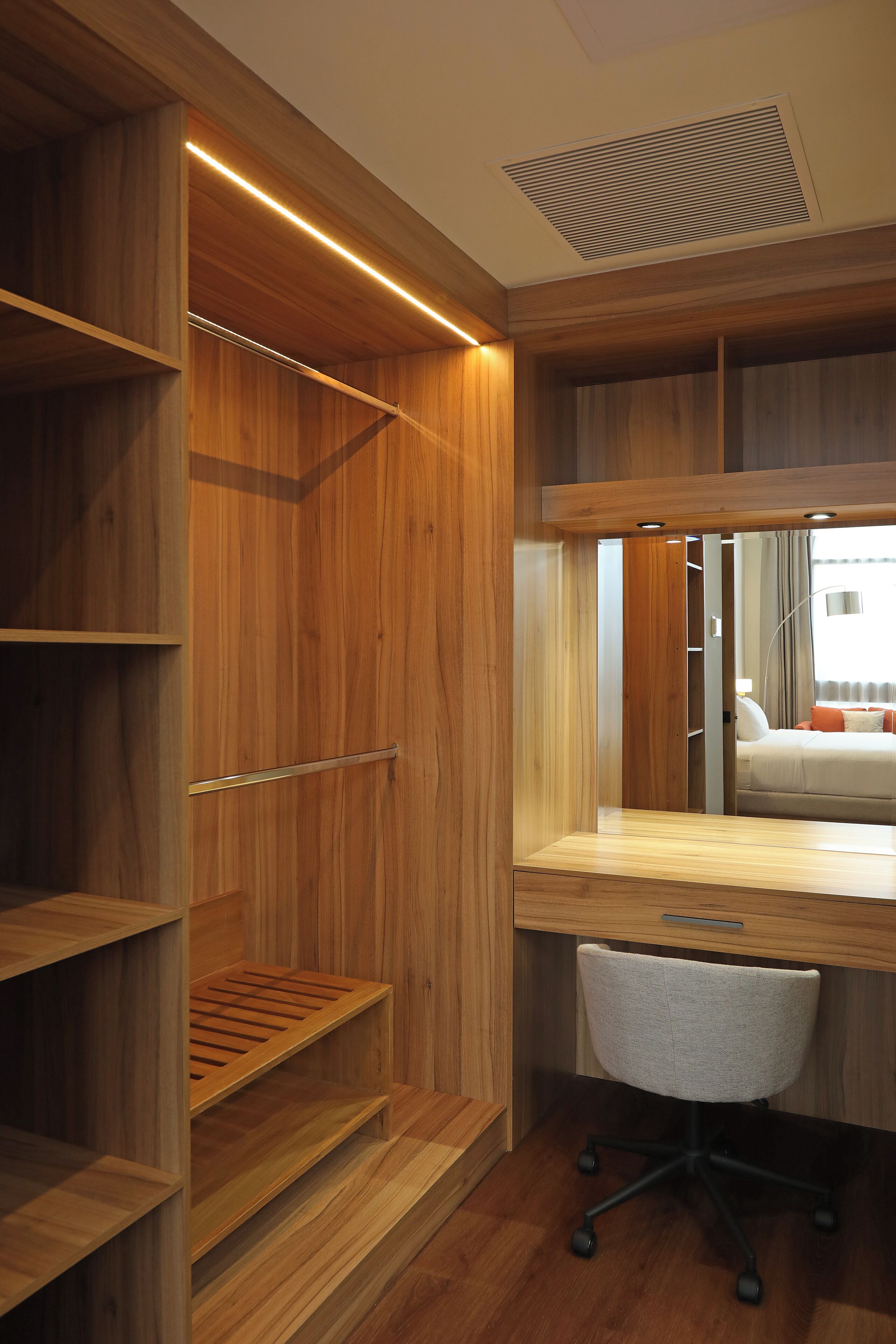 Une chambre à coucher moderne avec une armoire en bois, un bureau et une chaise.
