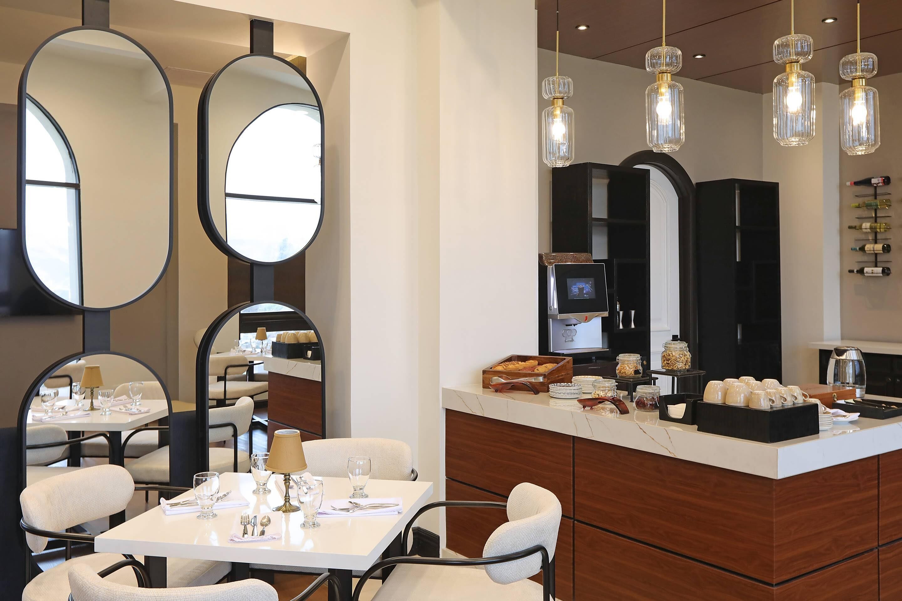 A modern dining area with round tables, chairs, and a central island with a coffee station.