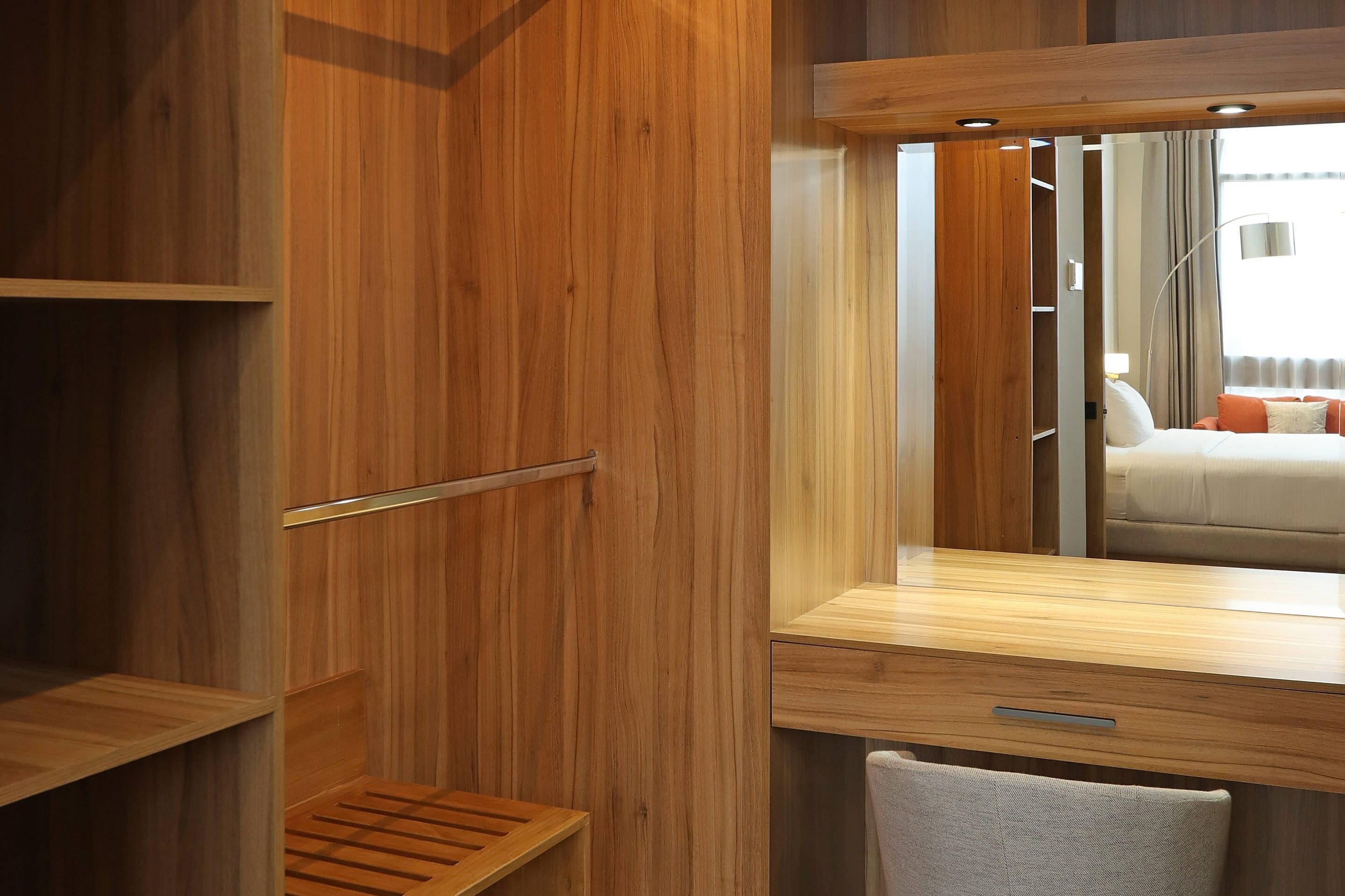 A wooden vanity with a mirror, a towel, and a shelf.