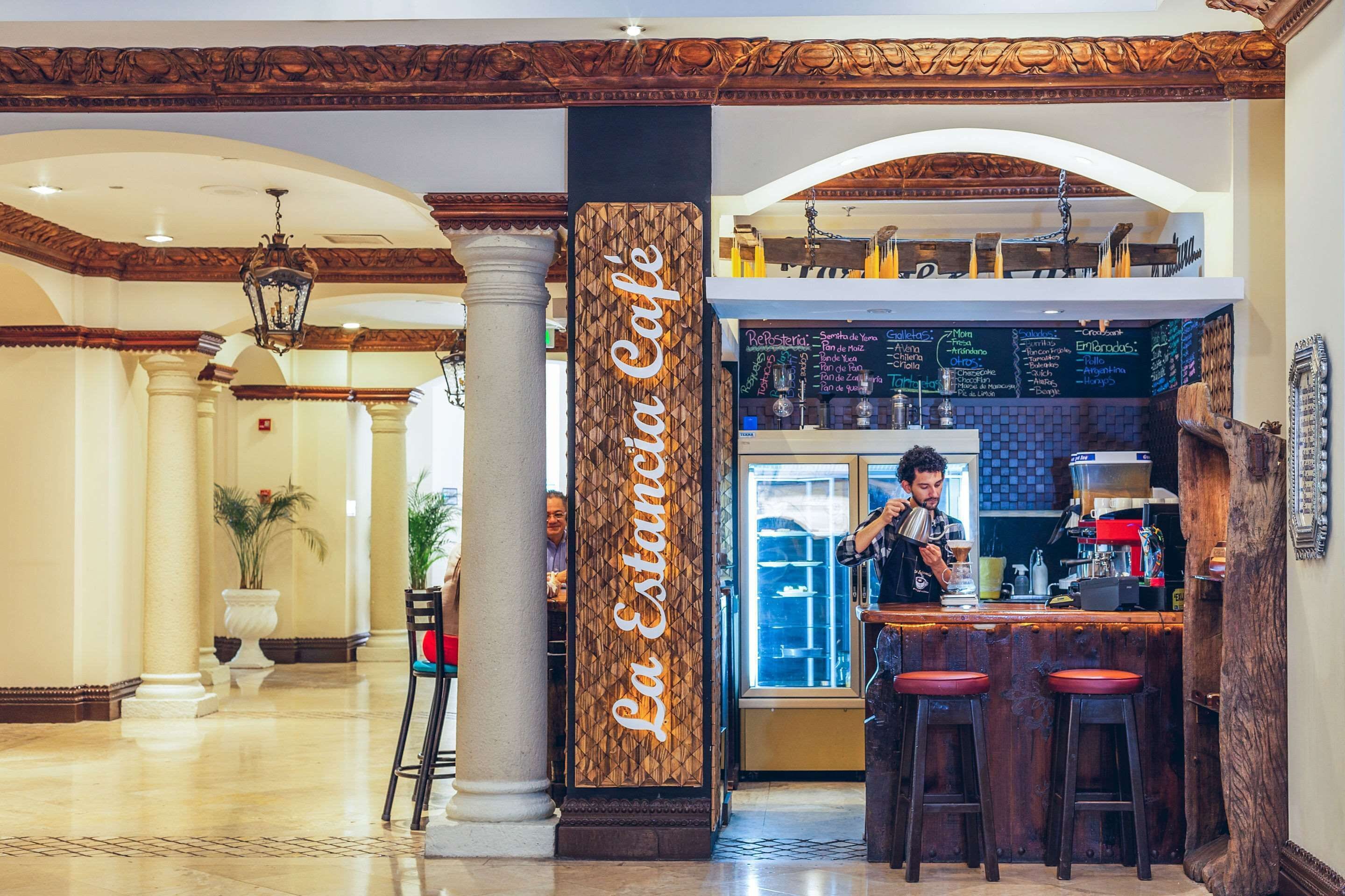 A café with a wooden sign, a bar area, and a menu board.