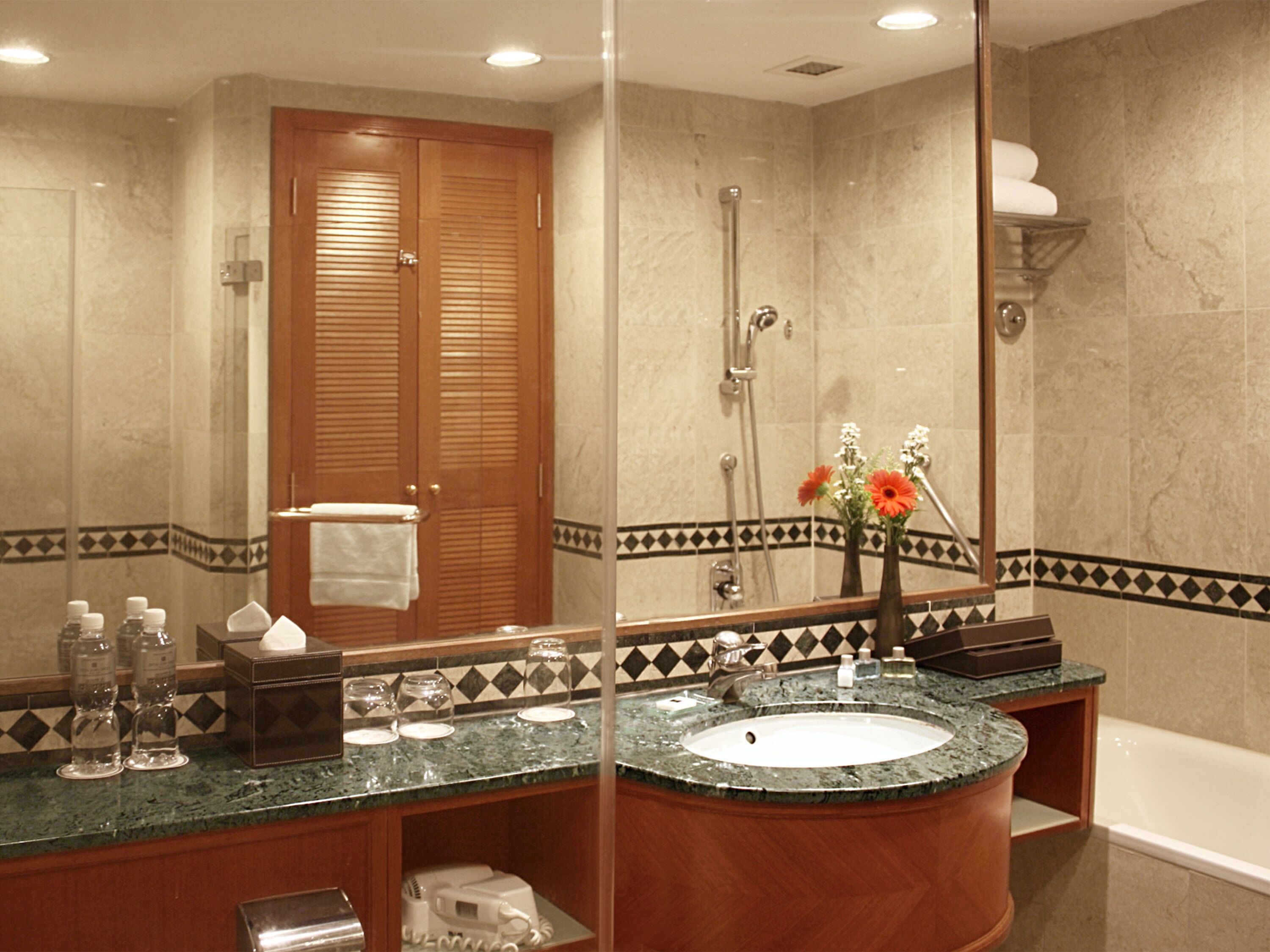 A bathroom with a marble sink, wooden vanity, and a large mirror.