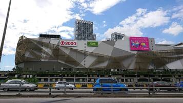 Een modern gebouw met een geometrisch gevelontwerp, een Sogo winkel en een bord met 'Village Grocer'.