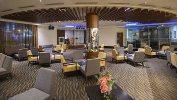 A hotel lobby with a central seating area, a large mirror, and a patterned carpet.